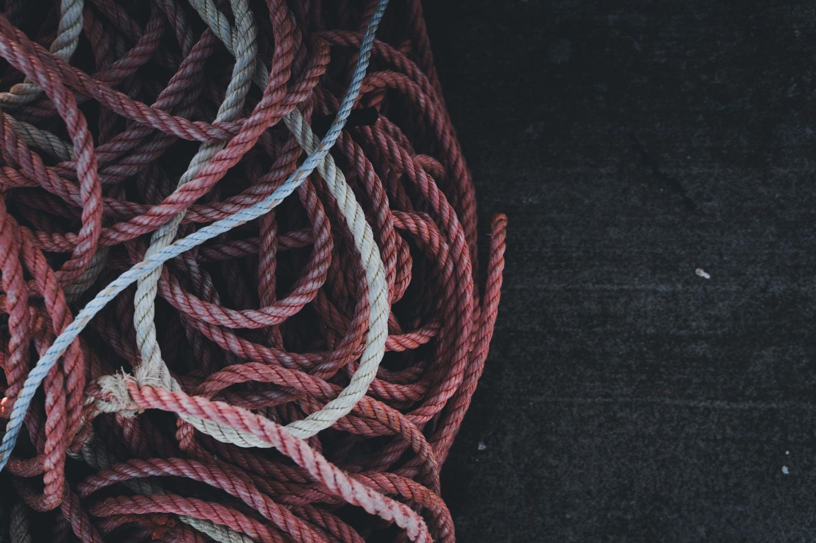 Karanlık bir odada tek başına oturmuş, elleri yüzünde, ağırlık altında görünen bir kişi — açıklanamayan huzursuzluğun ve bitkinliğin sahnesi
