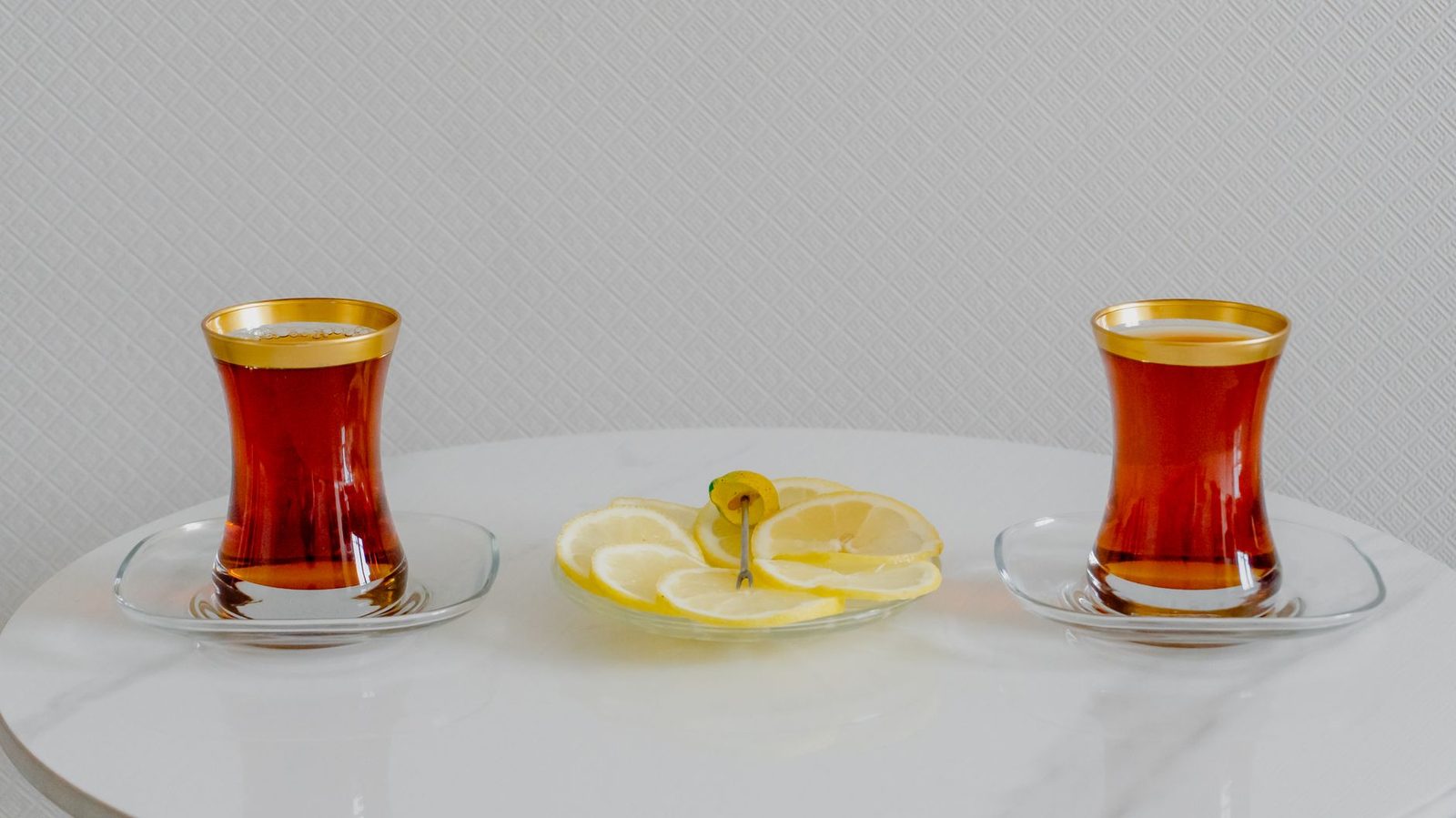 Huzurlu bir ev sofrasının köşesinde yan yana konmuş iki sıcak çay bardağı — barışın ve birlikteliğin sade temsili