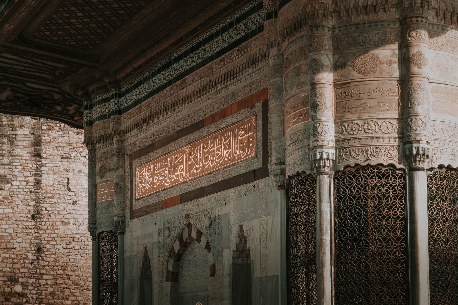 Cami duvarında oyulmuş Arapça hat yazısı ve çevresindeki geometrik desenler