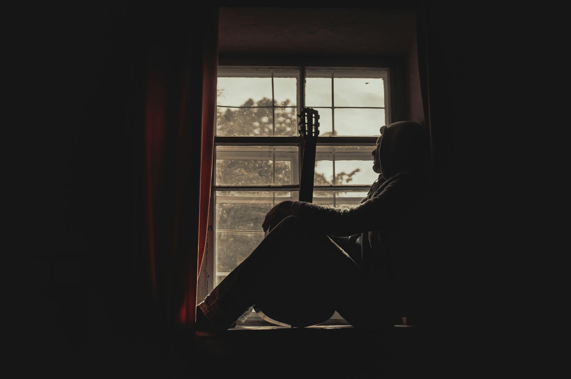 Pensive man sitting by a window in soft light, attention turned inward