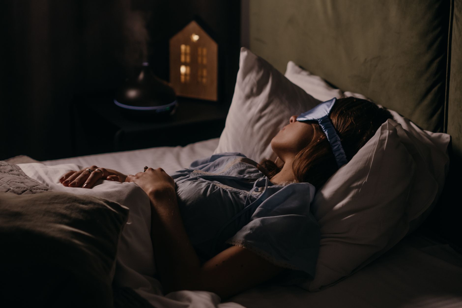 A woman asleep wearing an eye mask in soft blue light — the dream channel as the highest-signal feedback pathway