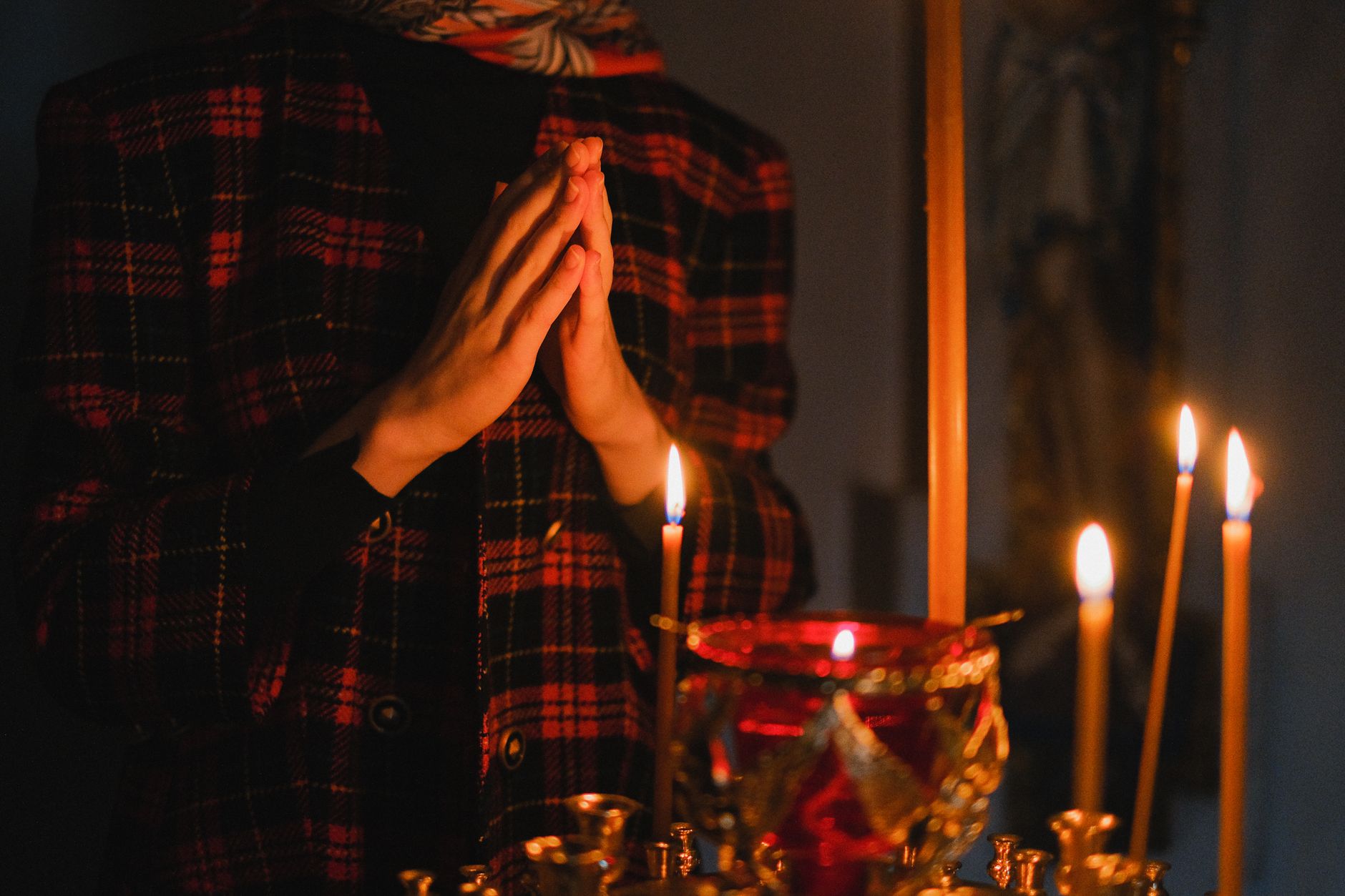 Person praying before lighted candles, the contemplative posture serious angelic work requires