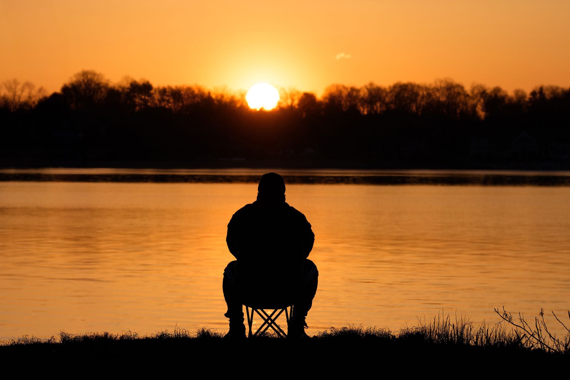 Silhouette meditator at sunrise on a quiet cove — effortless attention in deep practice