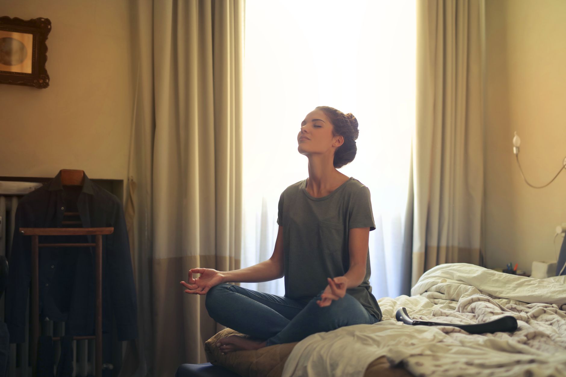 A person sitting in an upright meditation posture, spine stacked and settled-alert