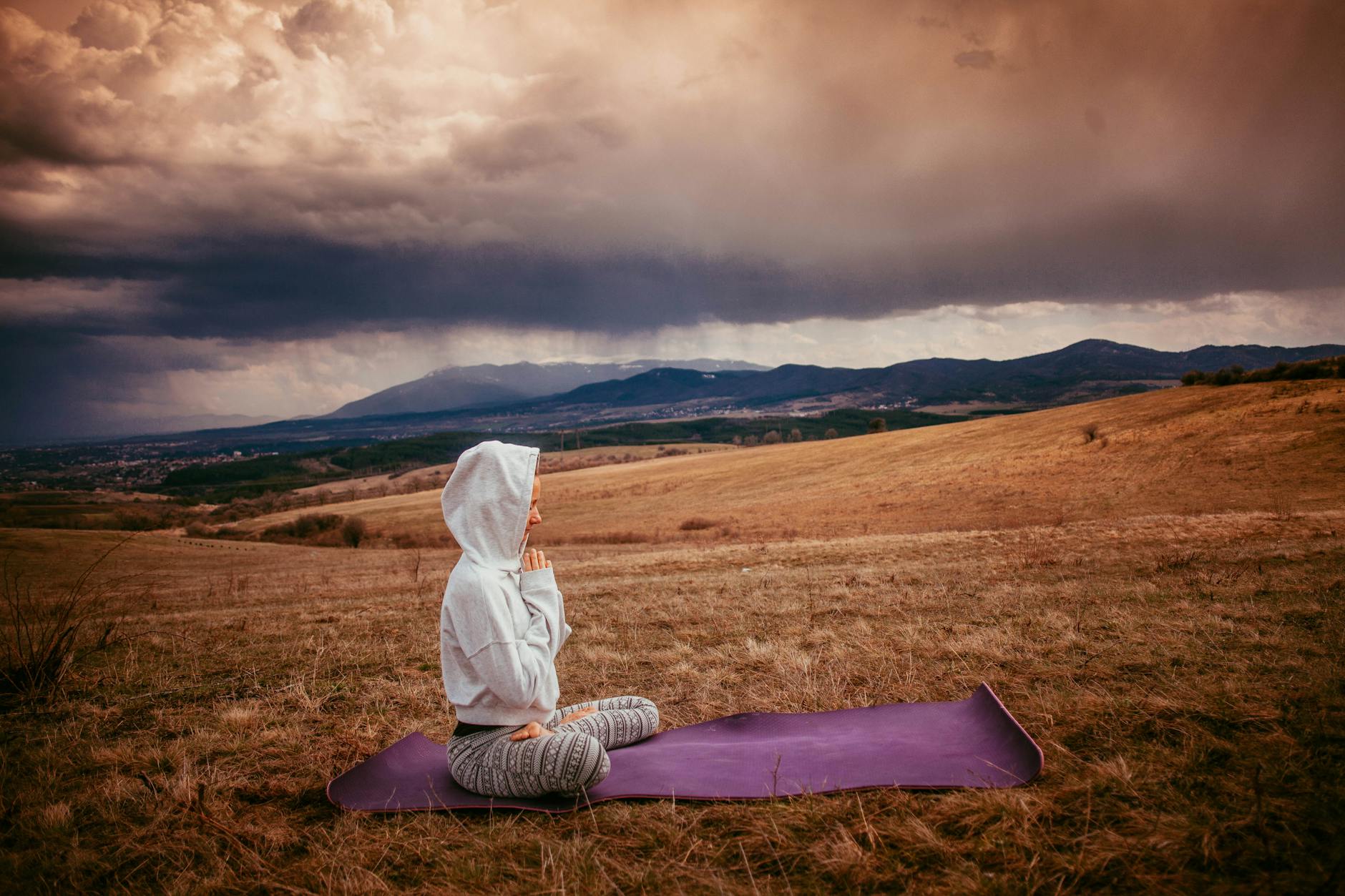 A person meditating on a mat, the practice at the center of modern well-being