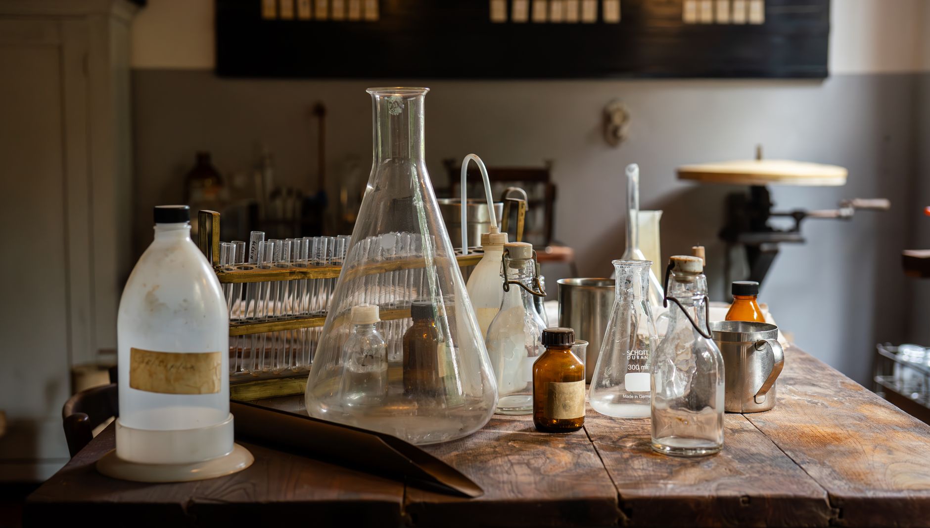 Vintage chemistry glassware and instruments on a table, evoking the alchemical laboratory as a teaching device for inner transformation