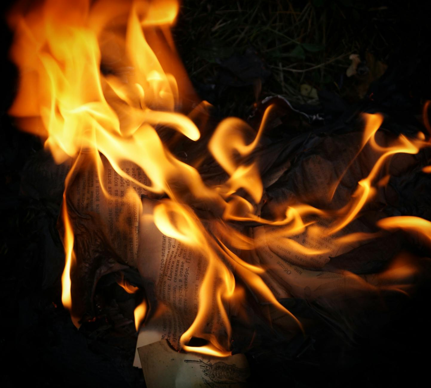 Burning papers closeup with flame and dark background, sigil destruction after activation