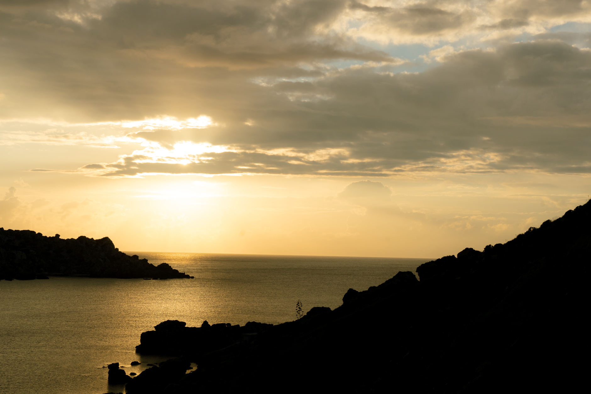 A sun setting over silhouetted mountains and sea, representing the solar current at the heart of western esoteric solar practice
