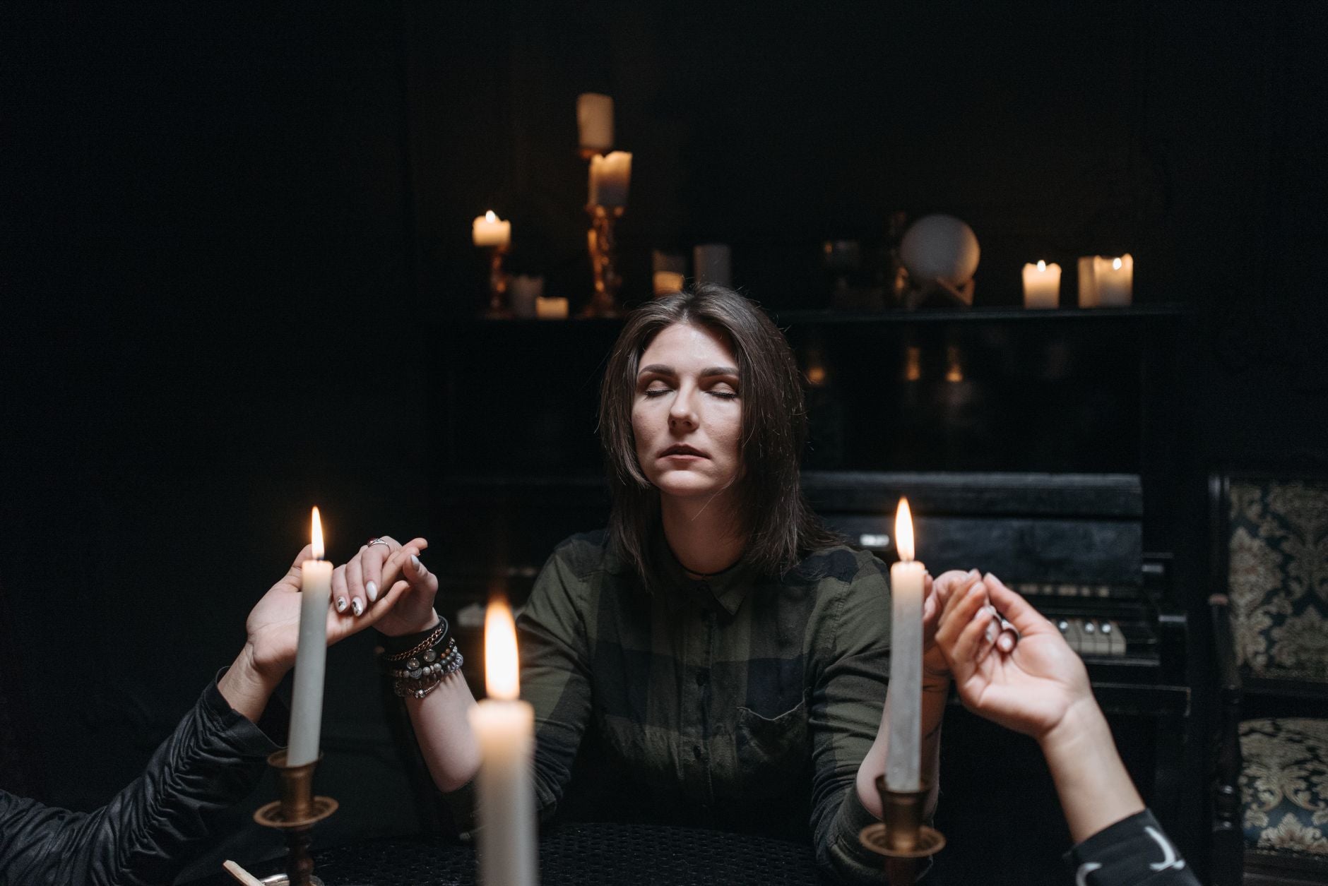 A practitioner with candles in a dark room, the moment of closing a ritual working