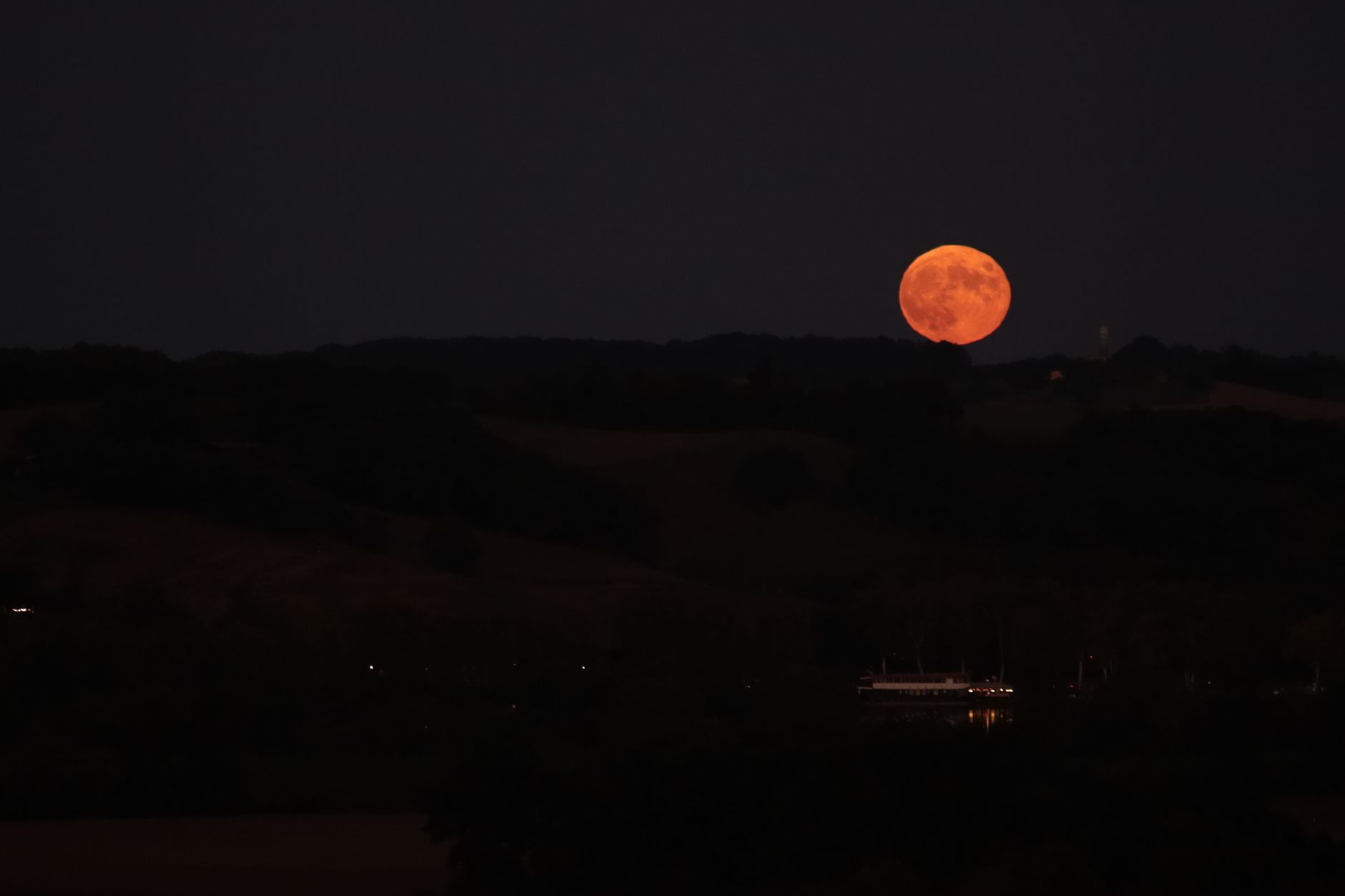 Full moon rising over a hillside with trees — the operating clock the classical traditions identified