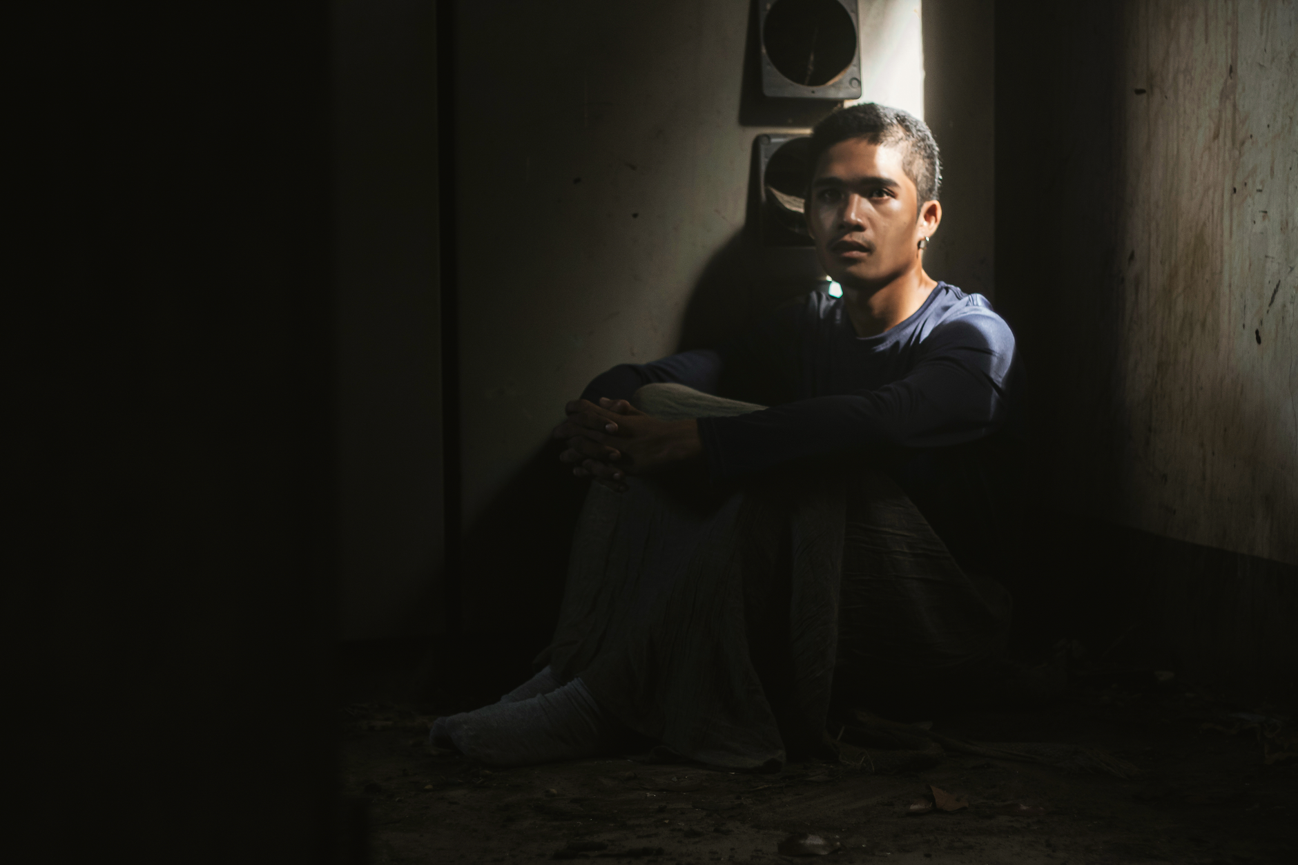 A person sitting quietly on the ground in soft light, settled and still