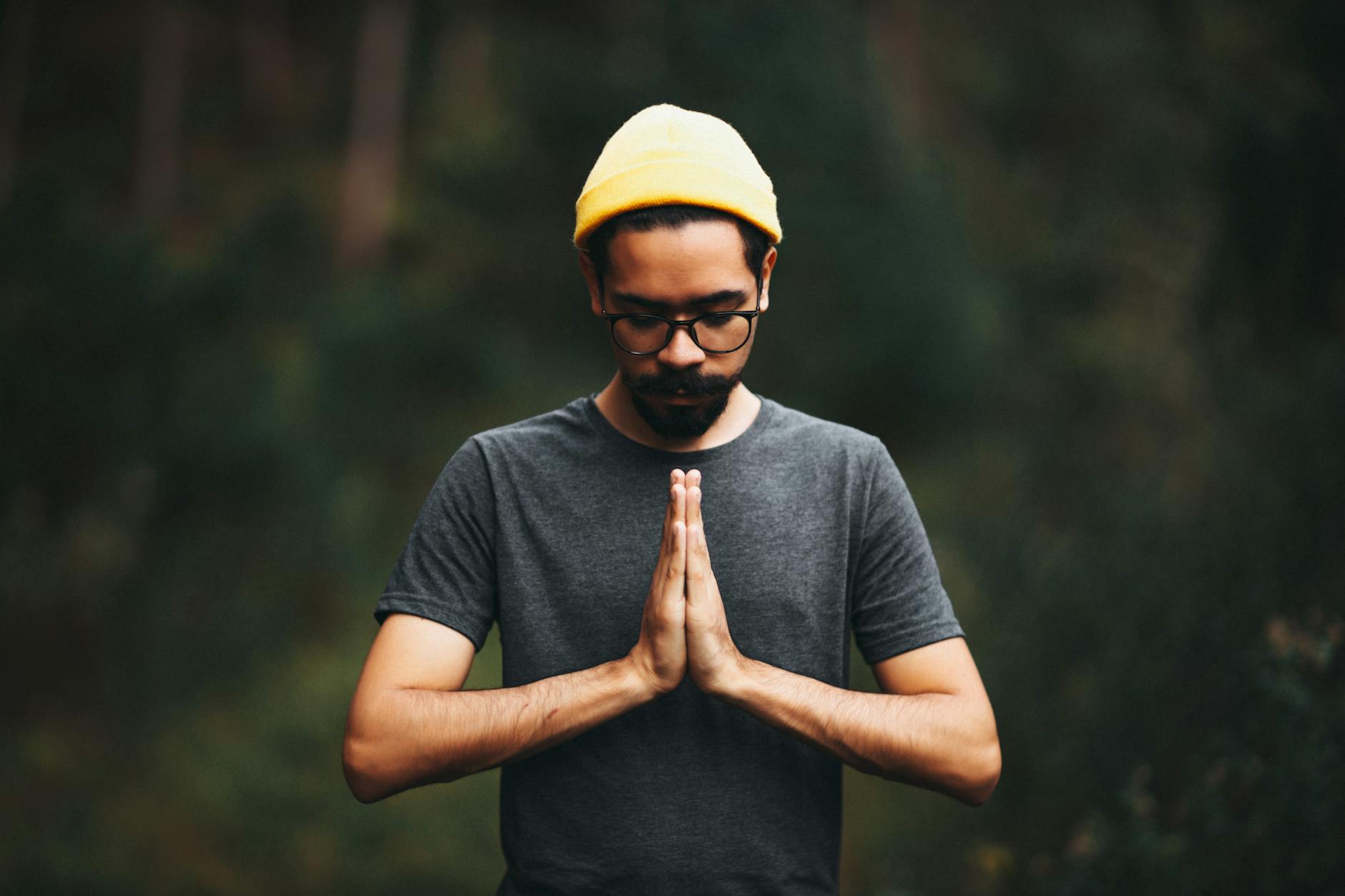 A focused man in a gray crew neck T-shirt and yellow knit cap, illustrating a stable inner state